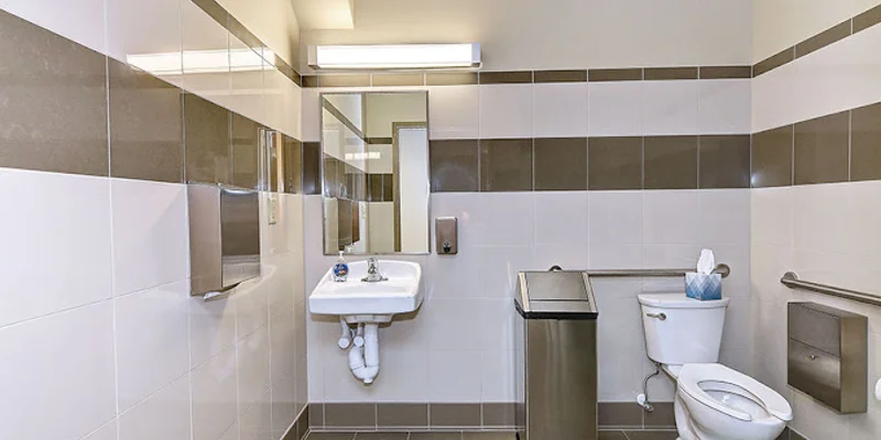 Modern bathroom with tile walls, sink, and accessible toilet.