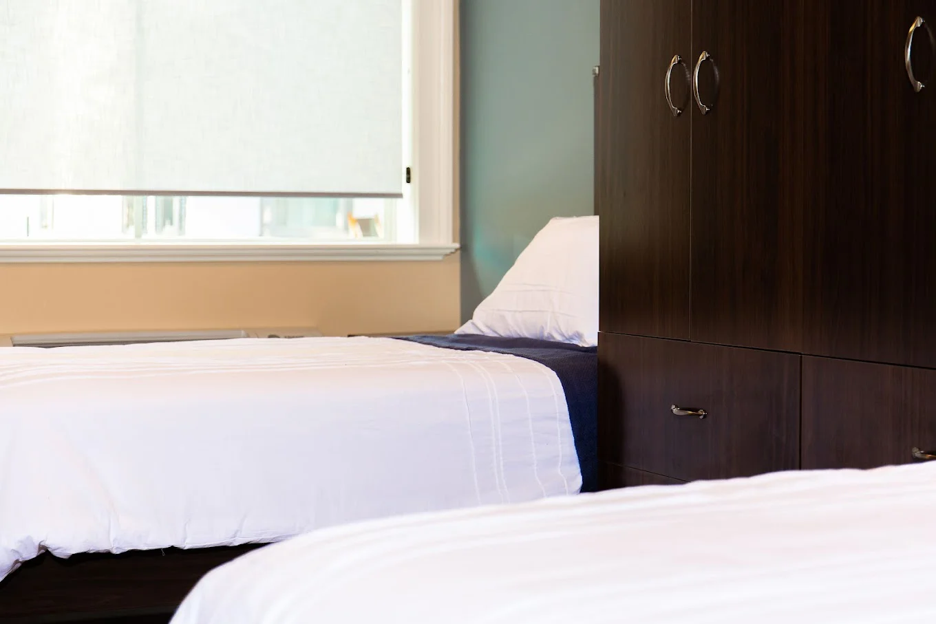 Dorm-style bedroom featuring two single beds and a dresser.