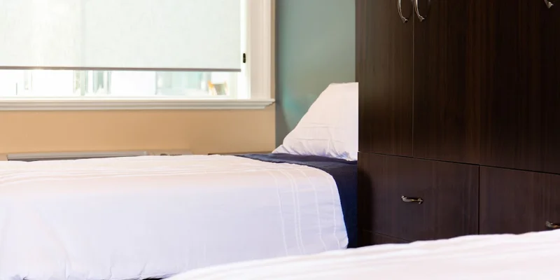 Dorm-style bedroom featuring two single beds and a dresser.