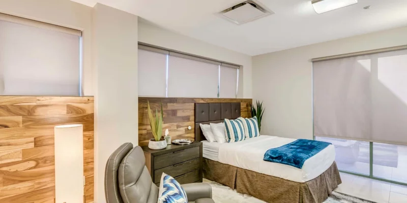 Bedroom with a made bed , an armchair, and a side-table.