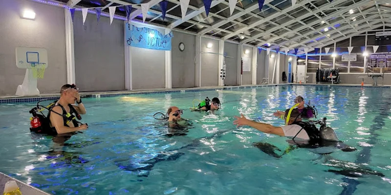Group of people learning scuba diving in an indoor pool.