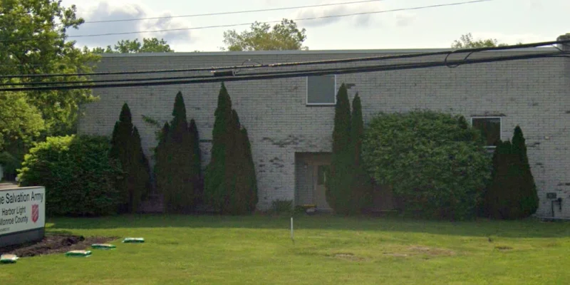  A light-colored building with neatly trimmed bushes and large trees providing a serene atmosphere.