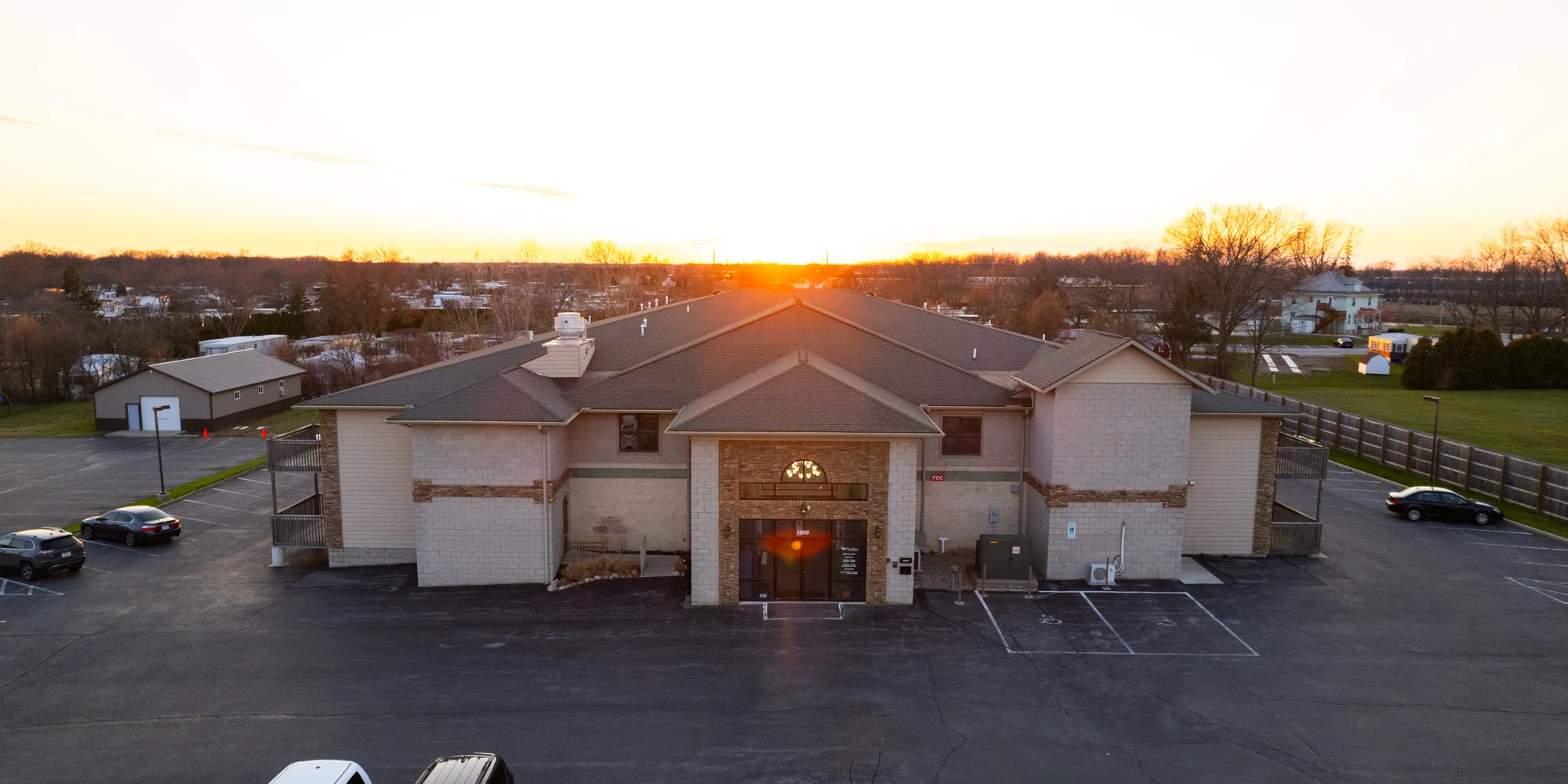 Rehab center exterior at sunset with large parking area