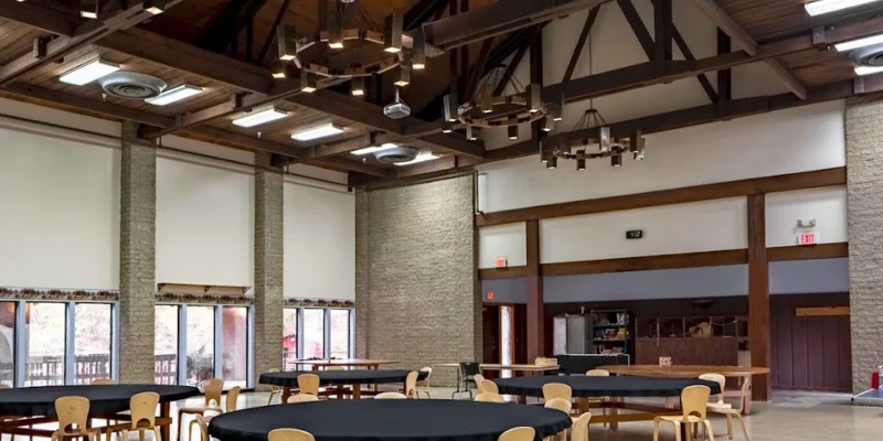 A high-ceiling dining hall with round tables and rustic chandeliers