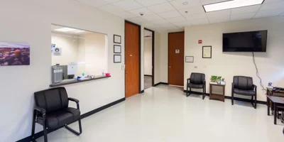 A reception area with seating and a check-in window at Symetria Recovery