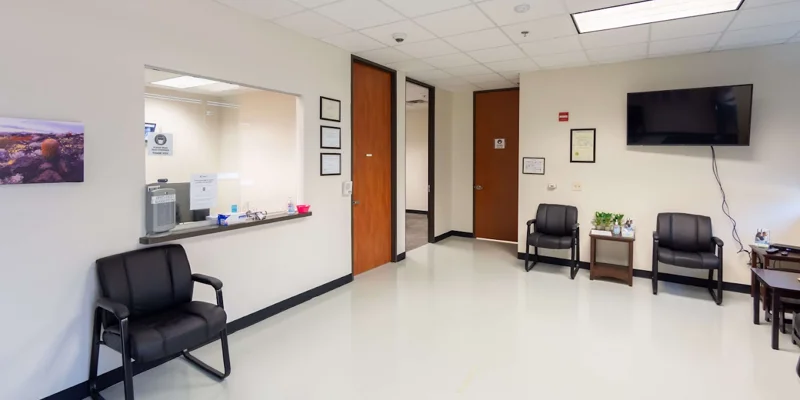 A reception area with seating and a check-in window at Symetria Recovery