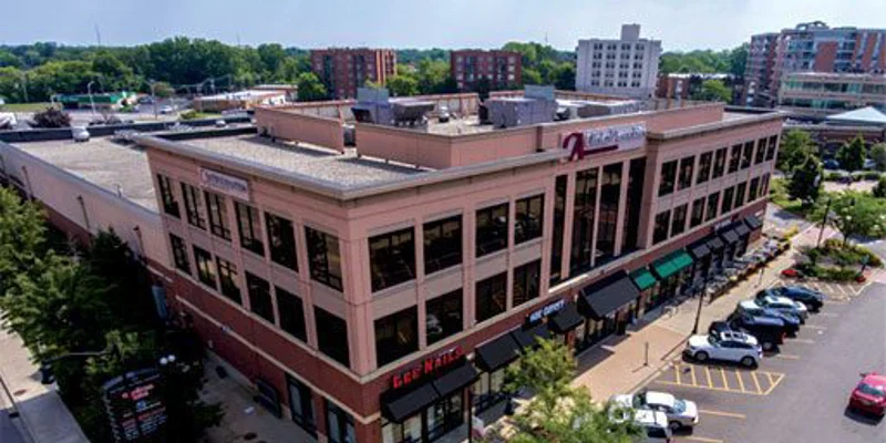 A large two-story commercial building with parking and businesses.
