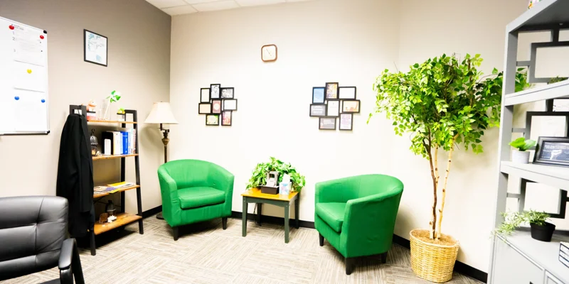 A well-lit office space with green chairs and decorative wall art.