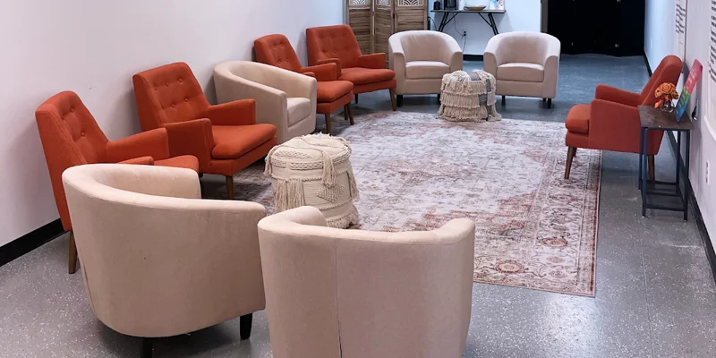 Group therapy room with orange and beige chairs in a circle.