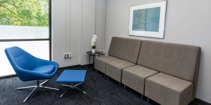  A lounge area with a blue chair and gray seating.