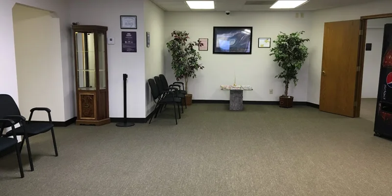 A waiting area with chairs, plants, and a glass display cabinet.