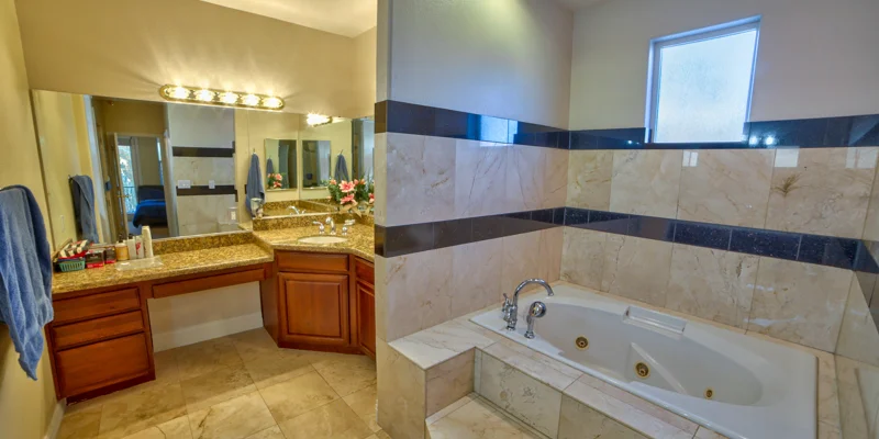 Bathroom with a jacuzzi tub, dual sinks, and cabinetry.