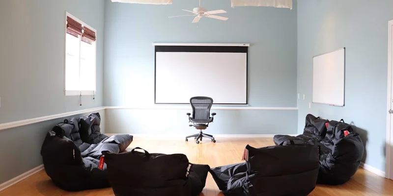 Therapy room with black bean bag chairs and a projector screen.