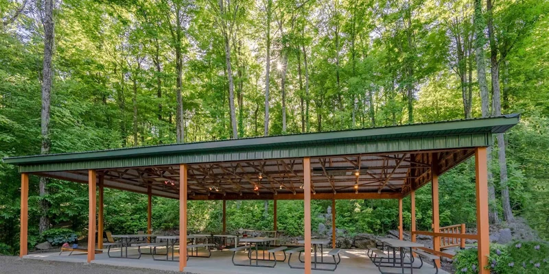 A rustic outdoor pavilion surrounded by lush green trees