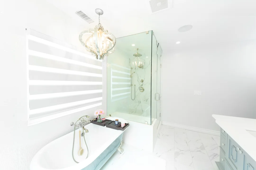 Bright white bathroom with chandelier and glass shower