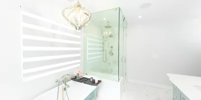 Bright white bathroom with chandelier and glass shower