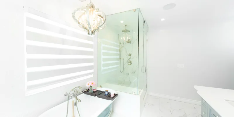 Bright white bathroom with chandelier and glass shower