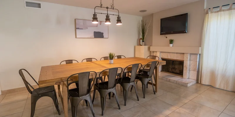 A dining area with a wooden table, chairs, and a fireplace.
