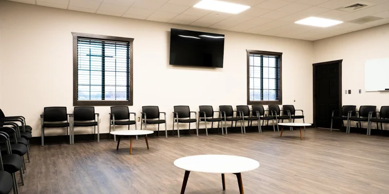  Spacious group therapy room with chairs and large windows.