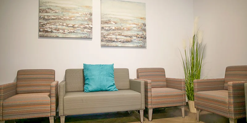 A waiting area with armchairs, a couch, and framed artwork on the wall.