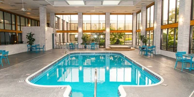 Pool area with tall windows and seating,
