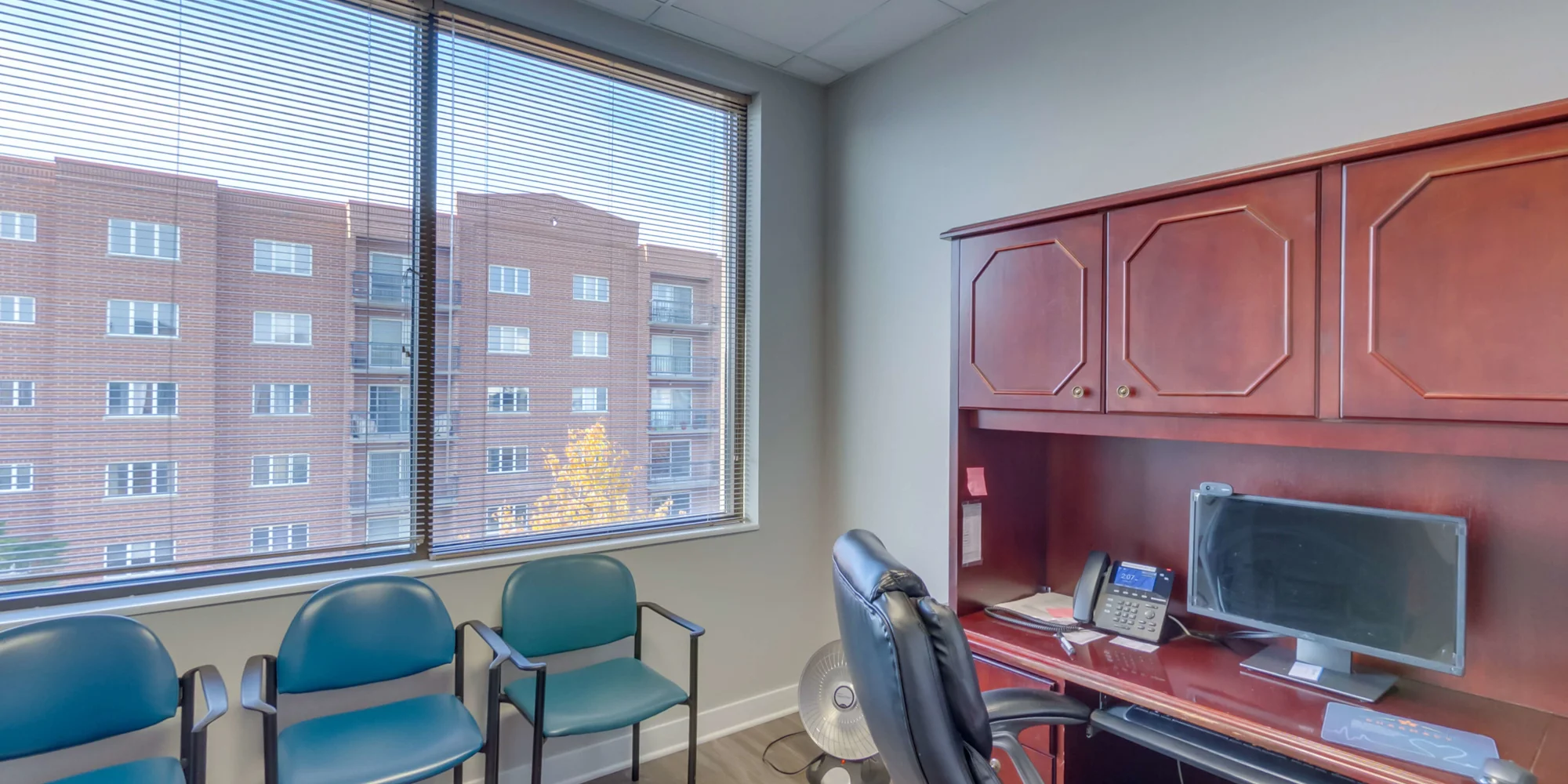 A small office with a desk, chairs, and a large window.