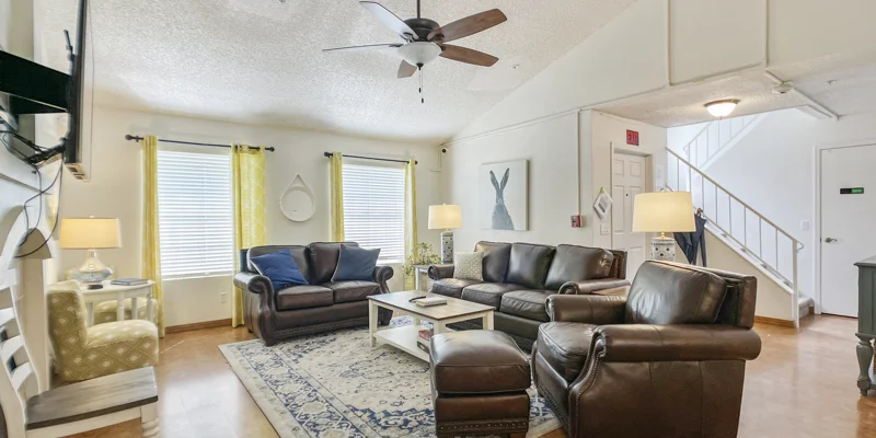 Living room with brown leather couches facing a TV.