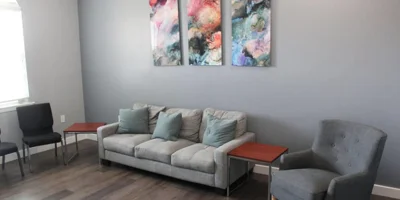 Therapy room with a couch, chairs and wall art.