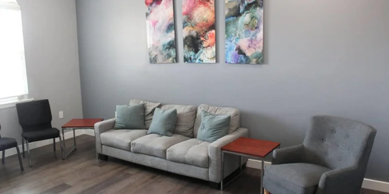 Therapy room with a couch, chairs and wall art.