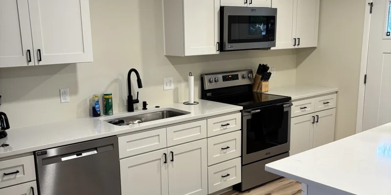Open kitchen-living space with island, fridge, and tan armchairs.