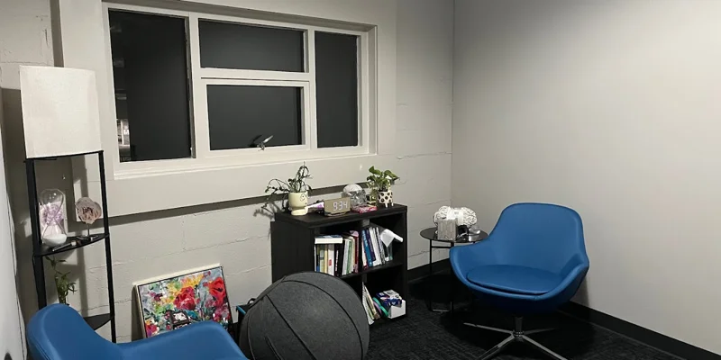 A therapy room with blue chairs and modern decorations.