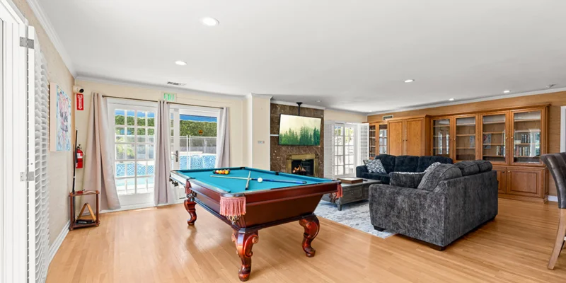 A game room with a pool table, fireplace, and lounge seating.