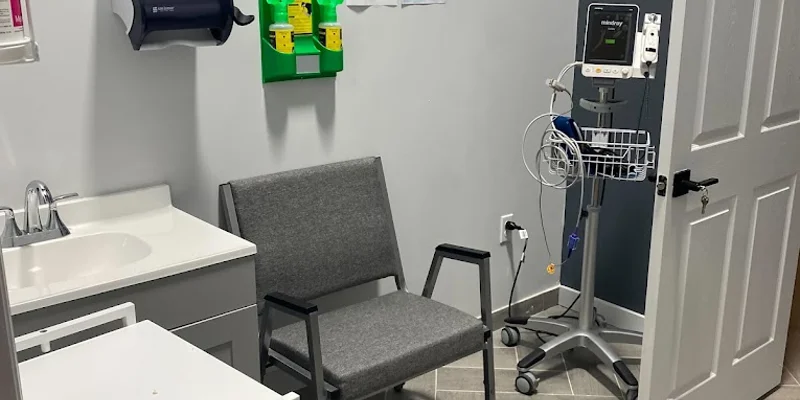 A small medical office with chairs and a medical monitor.