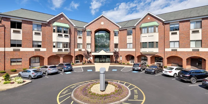 Exterior view of a brick rehab center with parking.