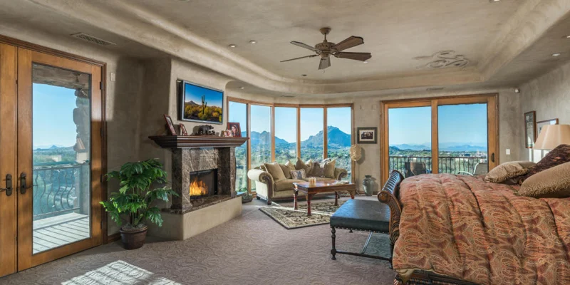 Bedroom with fireplace and scenic view.
