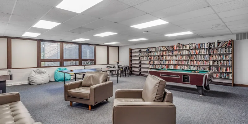 Rehab facility lounge with bookshelves, pool table, and seating area.
