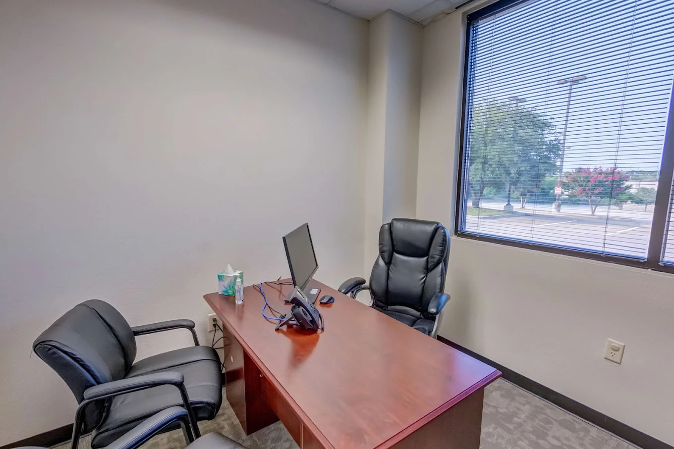 A private office with a desk, two chairs, and a window view