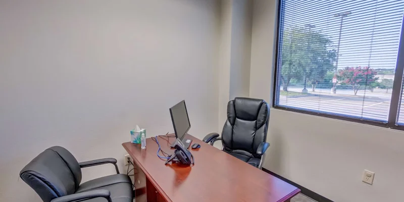 A private office with a desk, two chairs, and a window view