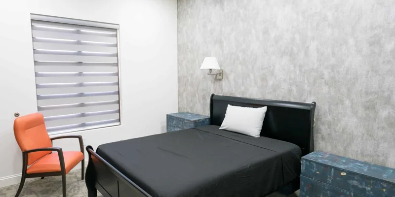 Bedroom with a black bed, gray walls, and a modern design.