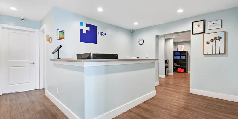 Reception desk with URP sign, light blue walls, and wood flooring.