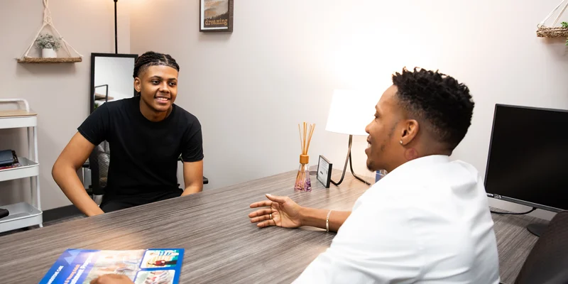 Private therapy session with two individuals at a desk.