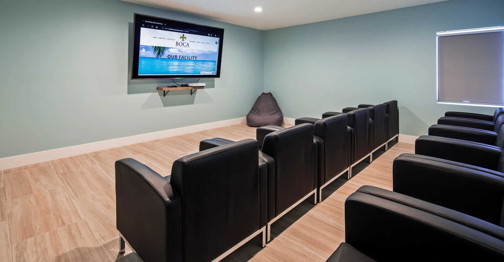 Theater room with black chairs and a screen.