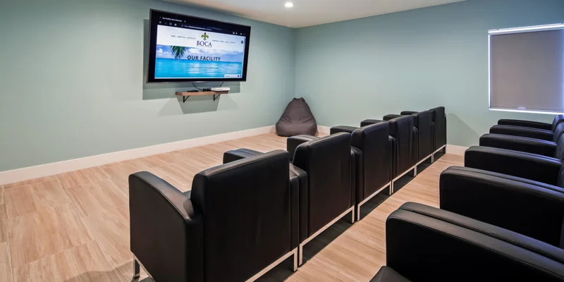Theater room with black chairs and a screen.