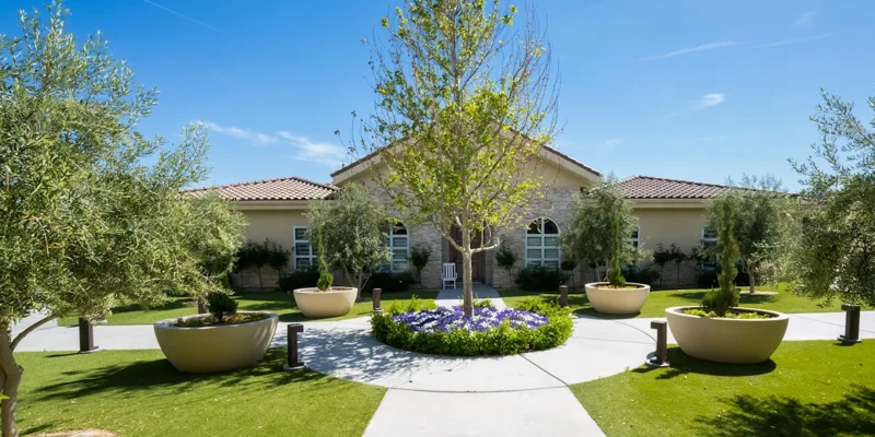 Rehab facility exterior with landscaped gardens and a central walkway.