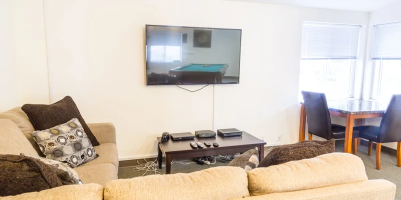 A living room with a sectional sofa, wall-mounted TV, and game table.