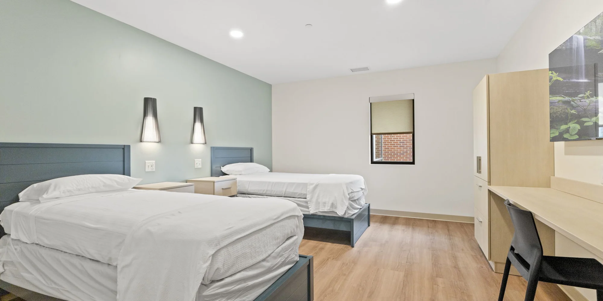 A bedroom with two beds, nightstands, and a window.