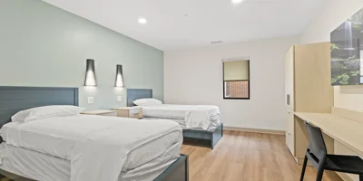 A bedroom with two beds, nightstands, and a window.