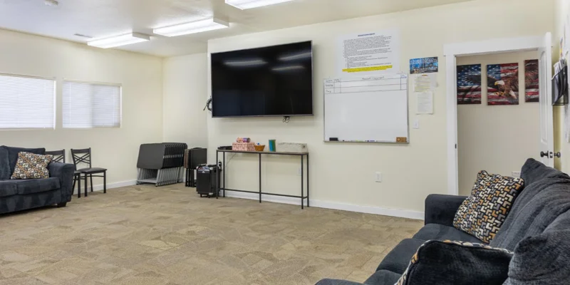 Meeting room with a large TV, whiteboard, and couches
