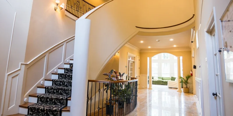  A grand staircase with an ornate railing inside a well-lit foyer