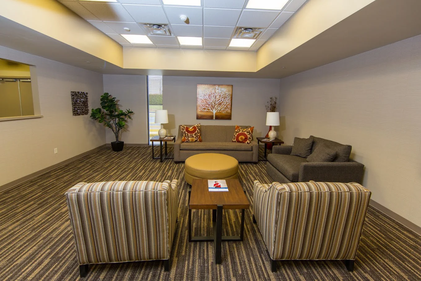 Indoor waiting area with striped armchairs and a central round ottoman